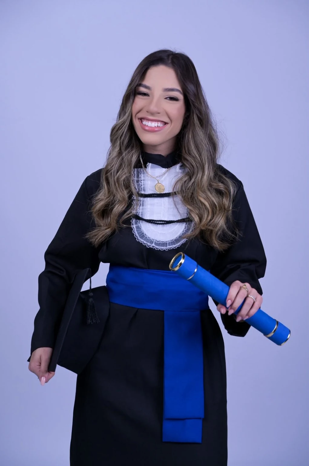 Vitória sorrindo com a beca e segurando o diploma